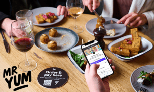 People eating around a table whilst using an app on a phone to pay